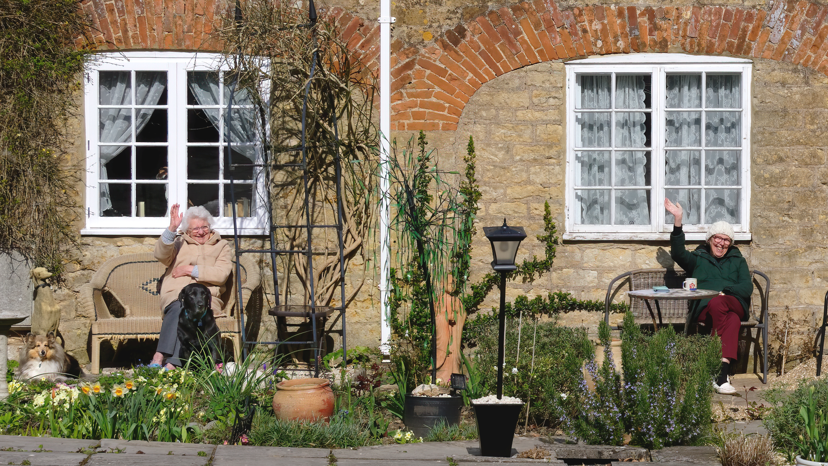 Two women social distancing outside their cottages