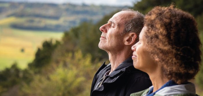 A couple with their eyes closed in a peaceful landscape