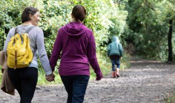 A couple walk on a forest track with a child walking further ahead