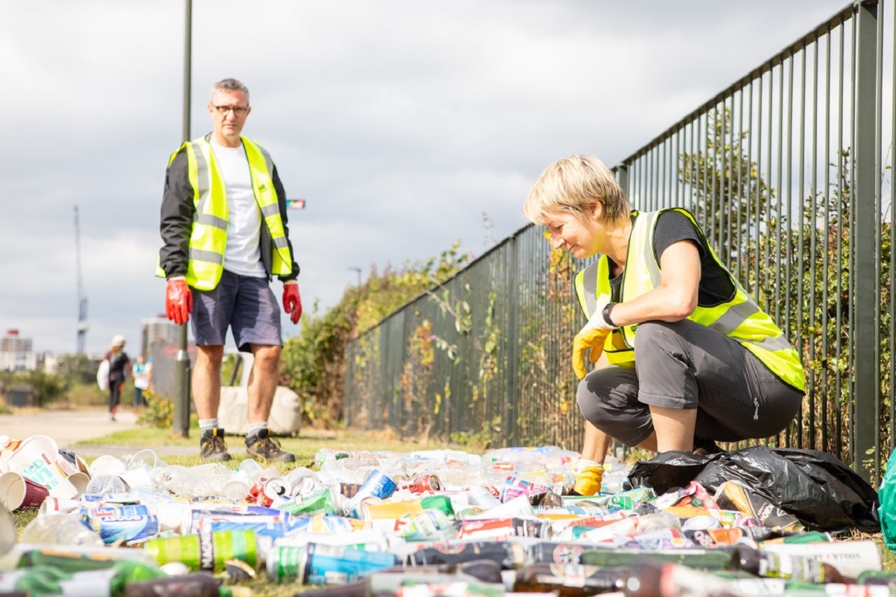 Two volunteers in hi-vis vests sorting litter