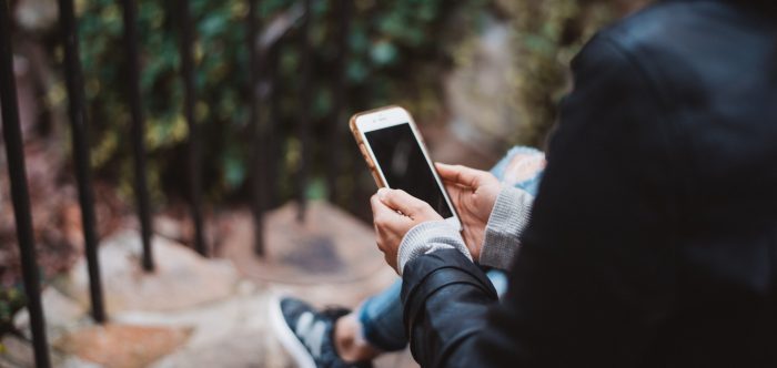 A woman looks at a phone in a forest