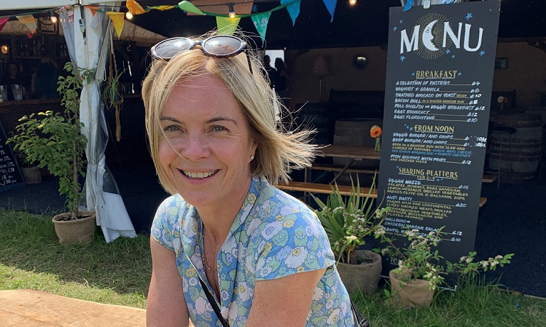 Mariella Frostrup sits on a bench at a festival