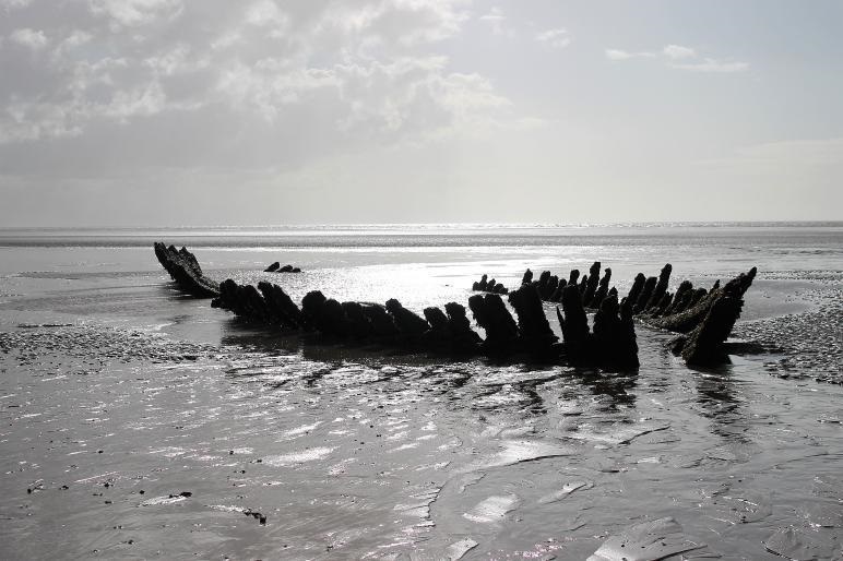 Remains of a shipwreck partially covered on beach