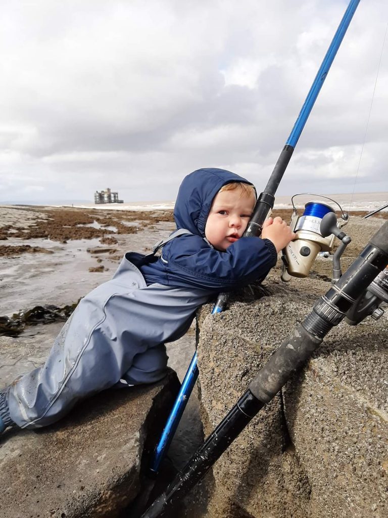 small boy and fishing rod on rocky beach