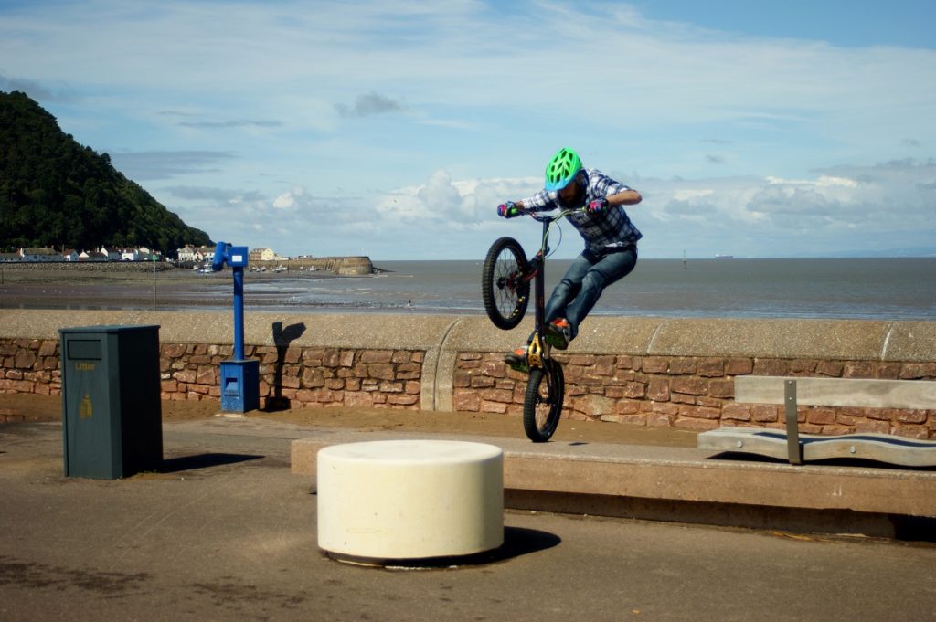 A BMX biker jumps on top of a concrete beam in Minehead