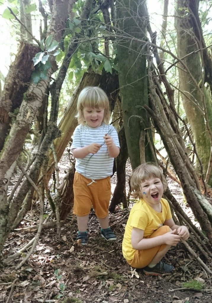 Two children play in a shelter in the woods