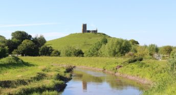 A picture of Burrow Mump with a river in the foreground