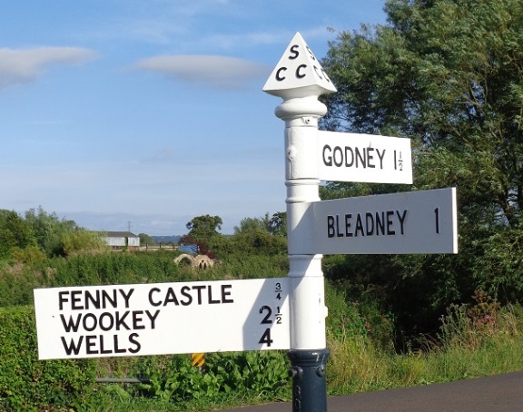 A fingerpost points left to Fenny Castle, Wookey and Wells; right to Godney and straight forward to Bleadney