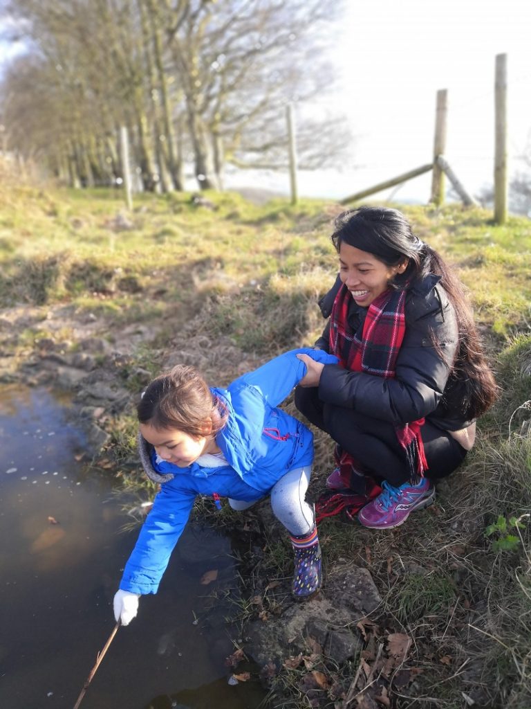 A mother holds her young child while they try pond dipping