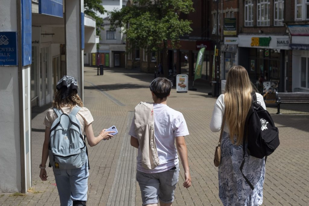 Three young people walk through a high street