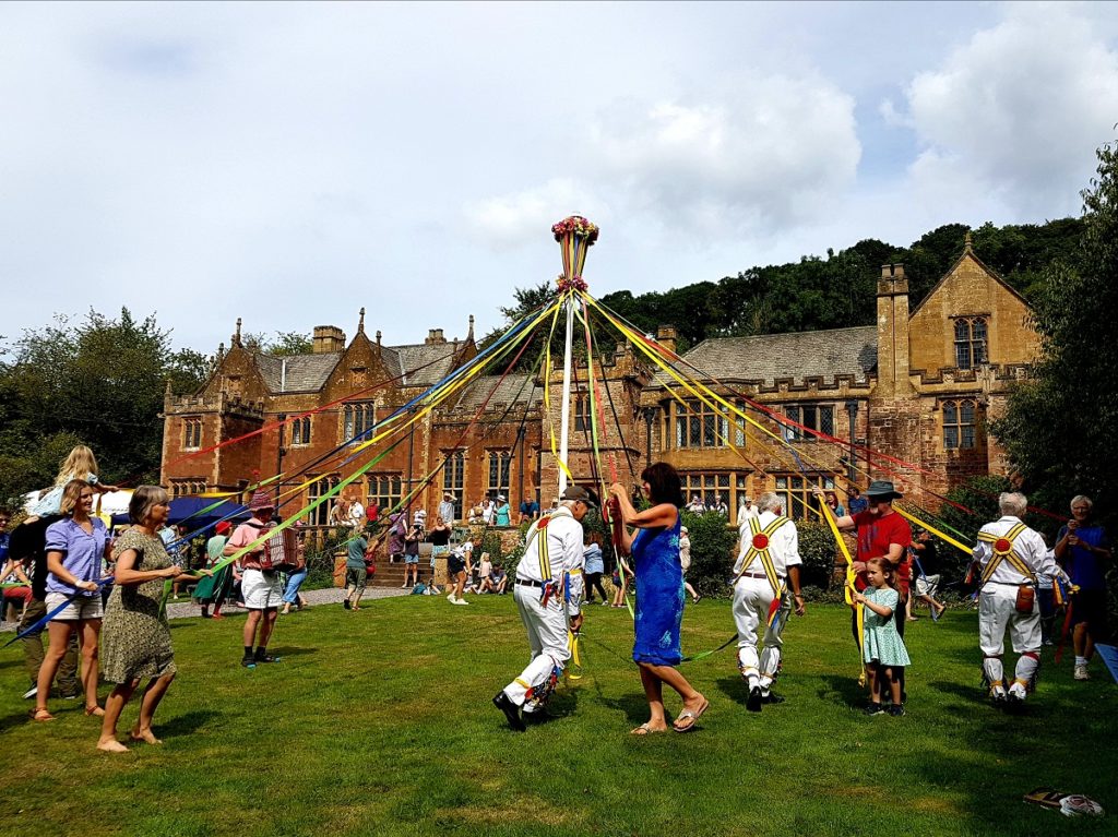 People dance around a maypole while wearing traditional clothing