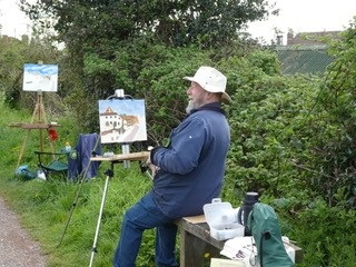 A man doing a painting on an easel in the open air