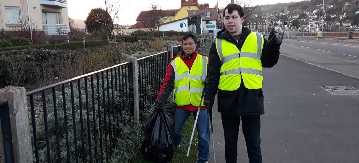 two people with hi-viz vests and litterpickers