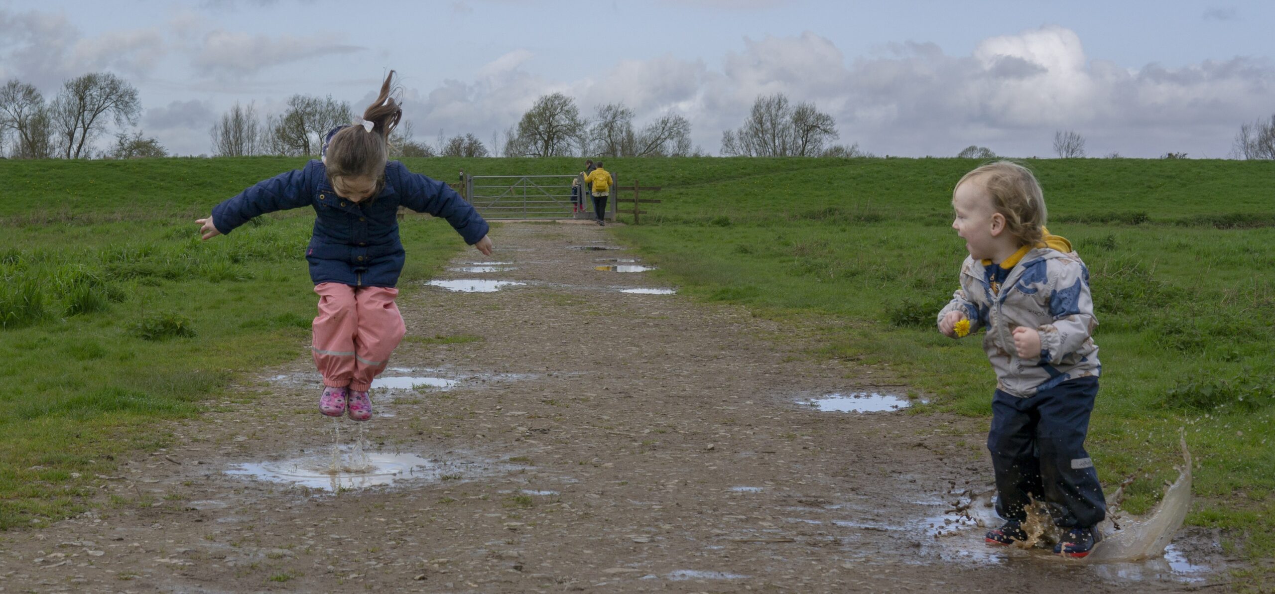 two small children jumping in puddles