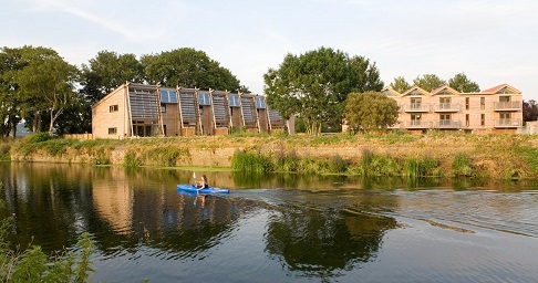canoeist on a river with modern houses in the background