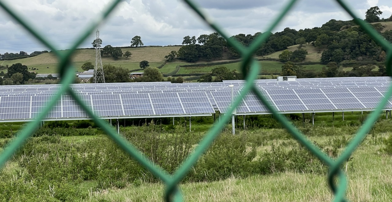 solar panels seen through a chainlink fence