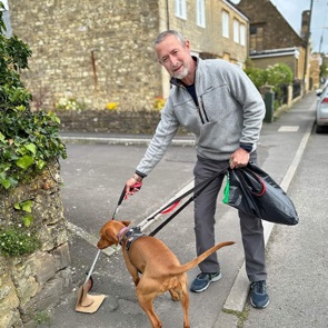 man collecting litter whilst walking a dog