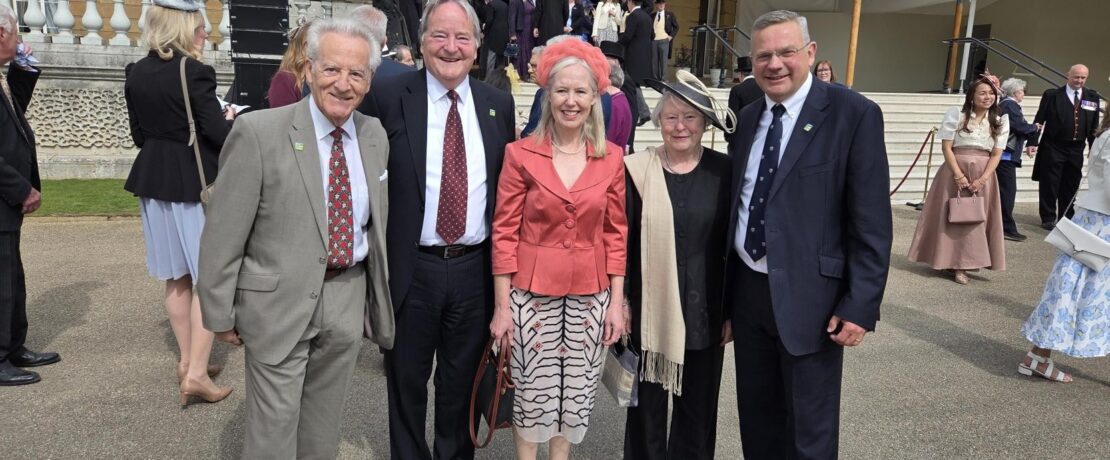a group of people in formal wear at the gates of Buckingham Palace