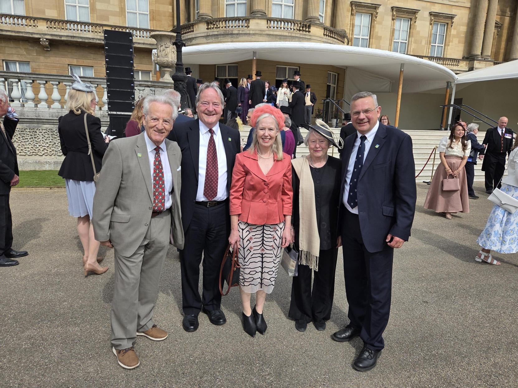 a group of people in formal wear at the gates of Buckingham Palace