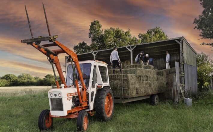 tractor with people stacking hay bales
