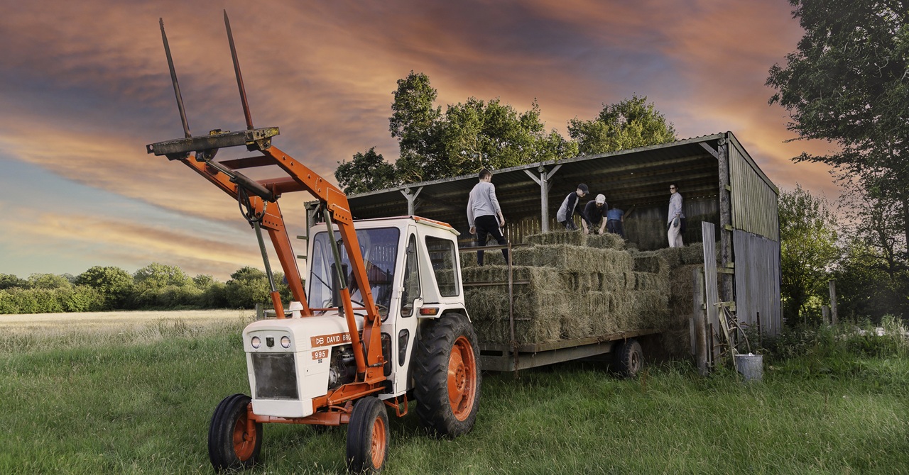 tractor with people stacking hay bales